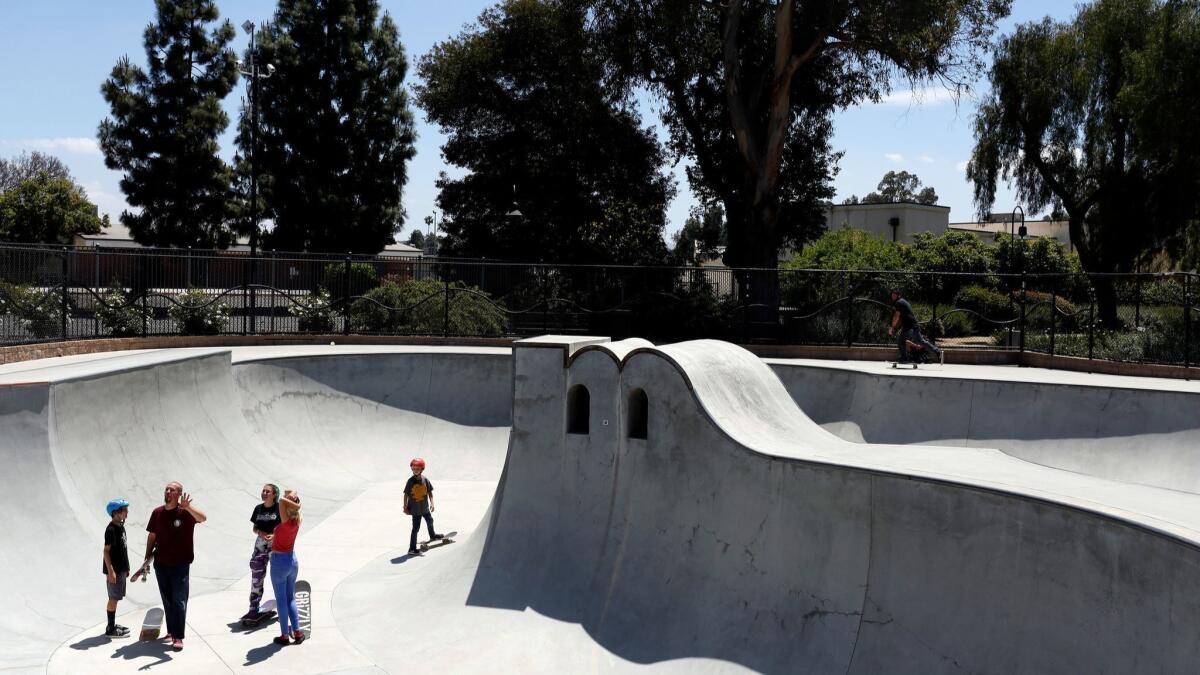 Skateboarders talk near a vertical pillar in the shape of an M for Moorpark at Poindexter Park.