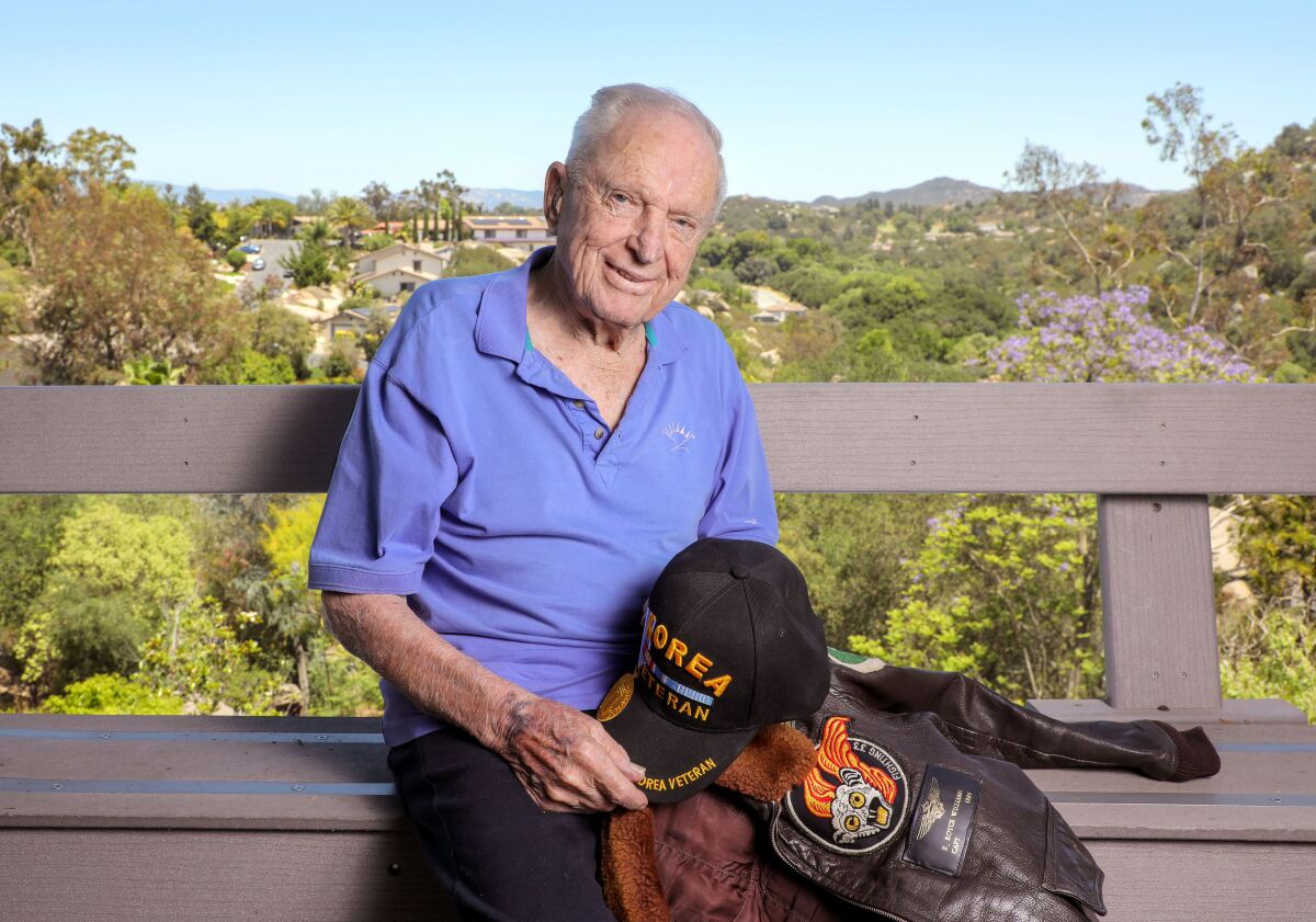 Retired U.S. Navy pilot Royce Williams, 97, holds one of his many caps and his flight jacket 