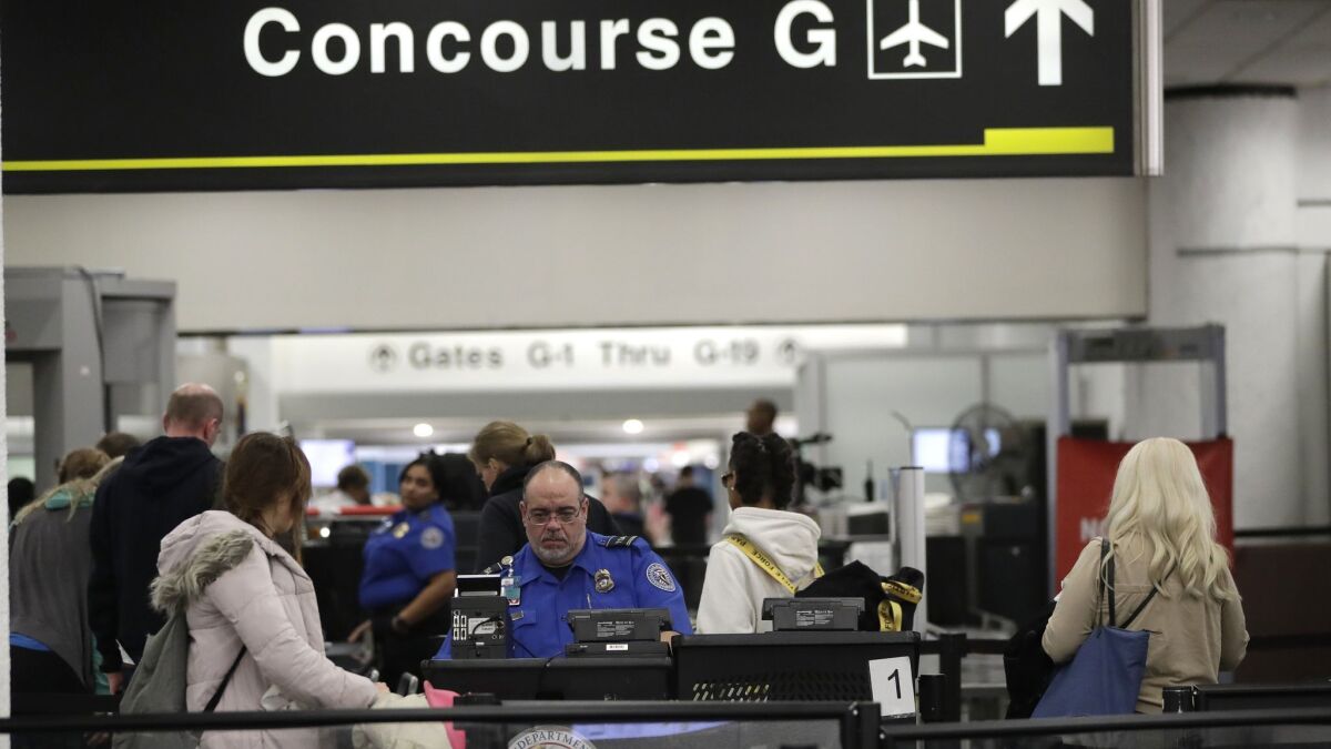 A Transportation Security Administration official works the entrance to Concourse G at Miami International Airport. The terminal is being closed this weekend as the federal government shutdown stretches toward a fourth week.