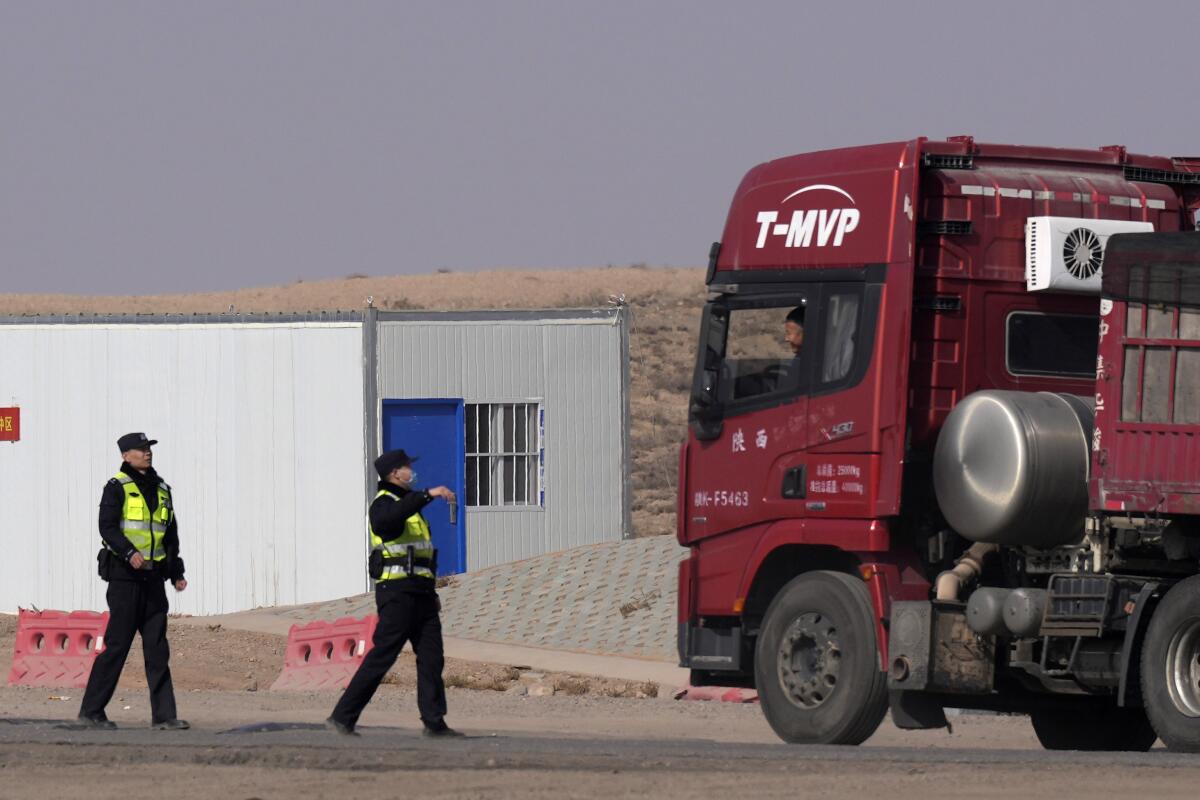 Police officers talking to a truck driver at a checkpoint