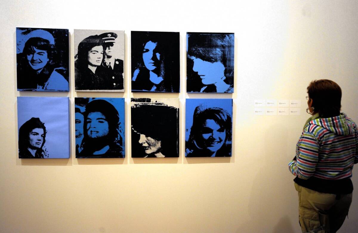 A visitor looks at paintings of former First Lady Jacqueline Lee Bouvier Kennedy Onassis, from Andy Warhol's series "Jackie, 1964" in Bogota. )
