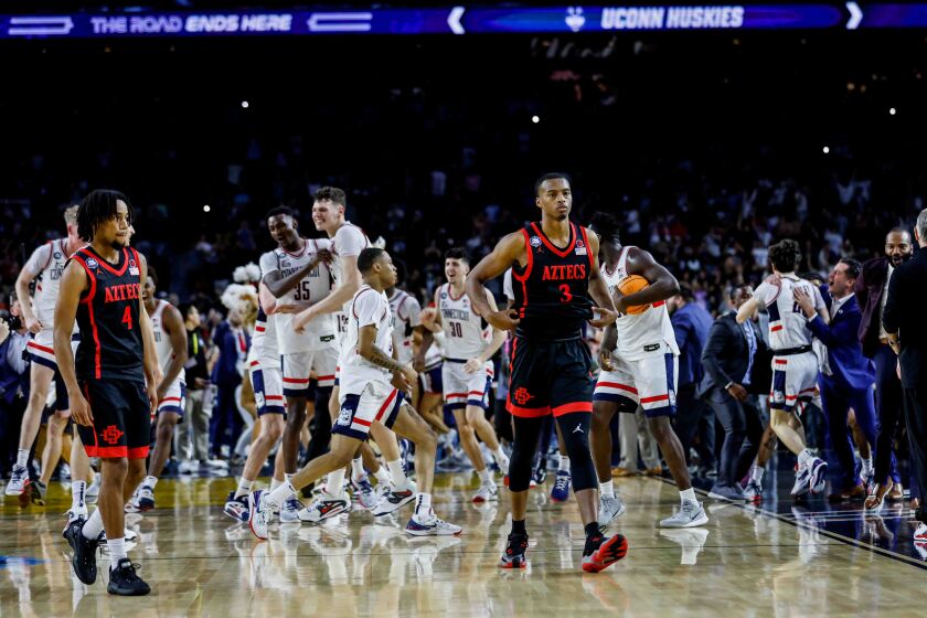 Houston, TX - April 3: San Diego State guard Jared Barnett (4), left, nd San Diego State guard Micah Parrish (3) walk off the court as Connecticut players celebrate after the national championship game of the 2023 NCAA MenOs Basketball Tournament played between the San Diego State Aztecs and the Connecticut Huskies at NRG Stadium on Monday, April 3, 2023 in Houston, TX. (K.C. Alfred / The San Diego Union-Tribune)