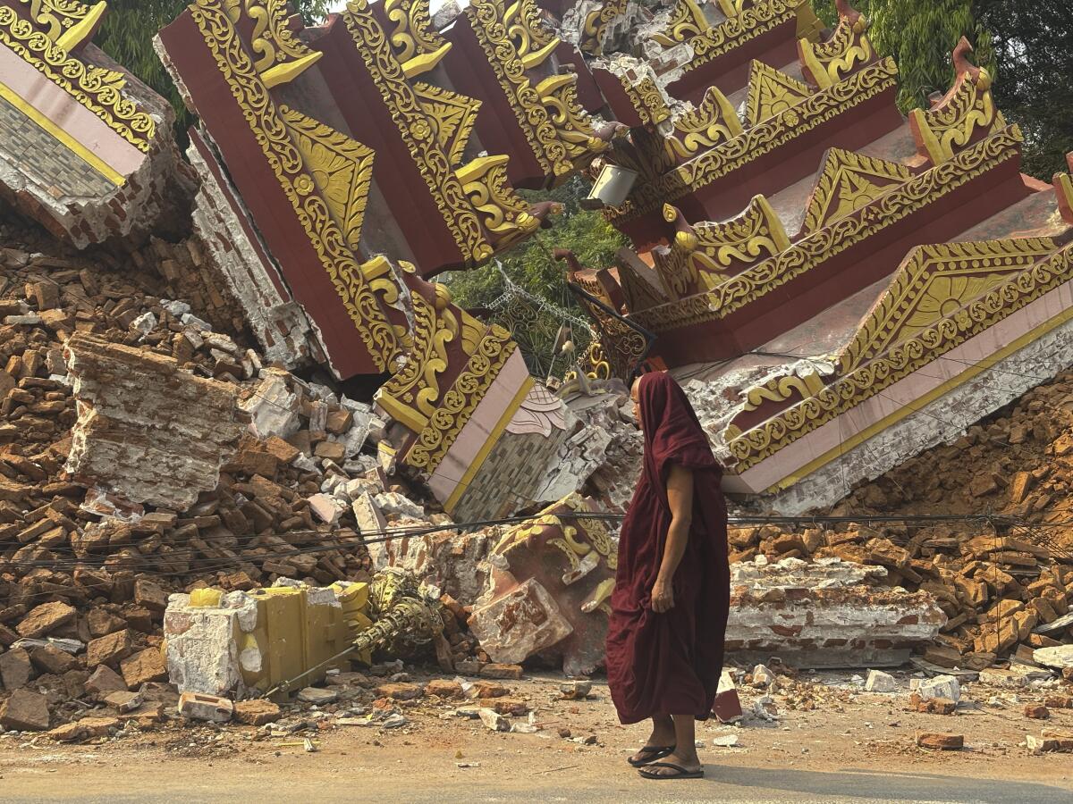 A Buddhist monk walks near a collapsed pagoda after an earthquake in Mandalay, central Myanmar.