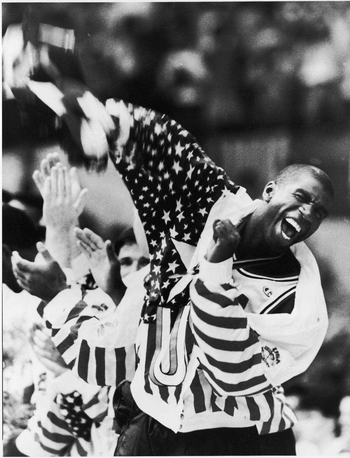 U.S. basketball player Earvin Magic Johnson screams as he lifts the American flag 