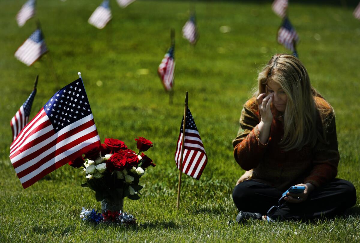 Shauna Chuchian sits next to the grave of brother Leonard Stewart on Sunday at Los Angeles National Cemetery. Her brother died in Vietnam in 1968.