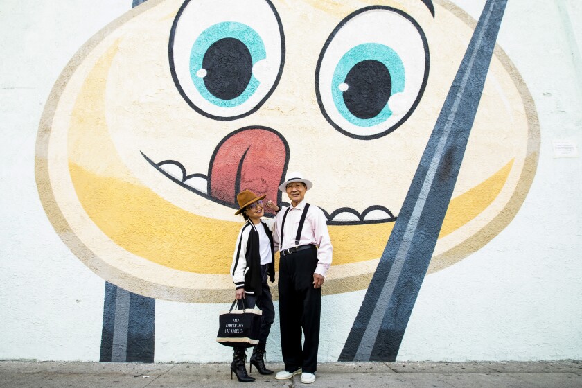 A daughter with her father stand in front of a wall painted with a smiling face
