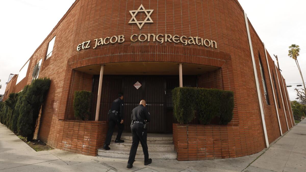 Los Angeles police officers head to the entrance of Etz Jacob Congregation/Ohel Chana High School to interview possible witnesses to a shooting by the synagogue's security officer.