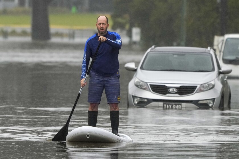 Man standing on a paddle board in a flooded street