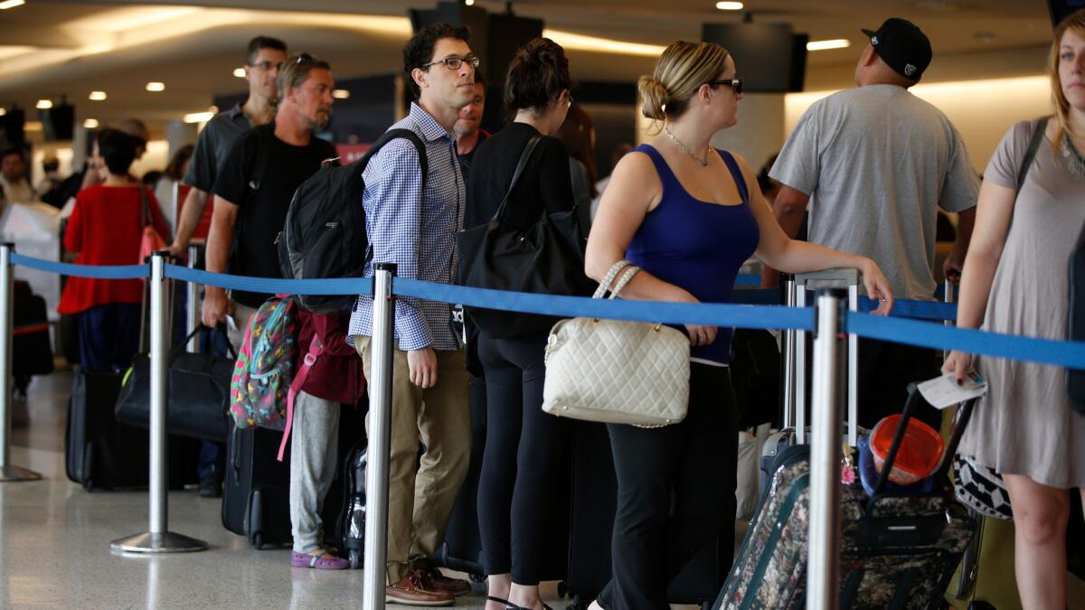 Travelers wait in long lines at the Delta Air Lines counter at LAX on the getaway day for the Labor Day holiday in September 2015. Airfares for this holiday weekend are expected to be lower than in the past few years.