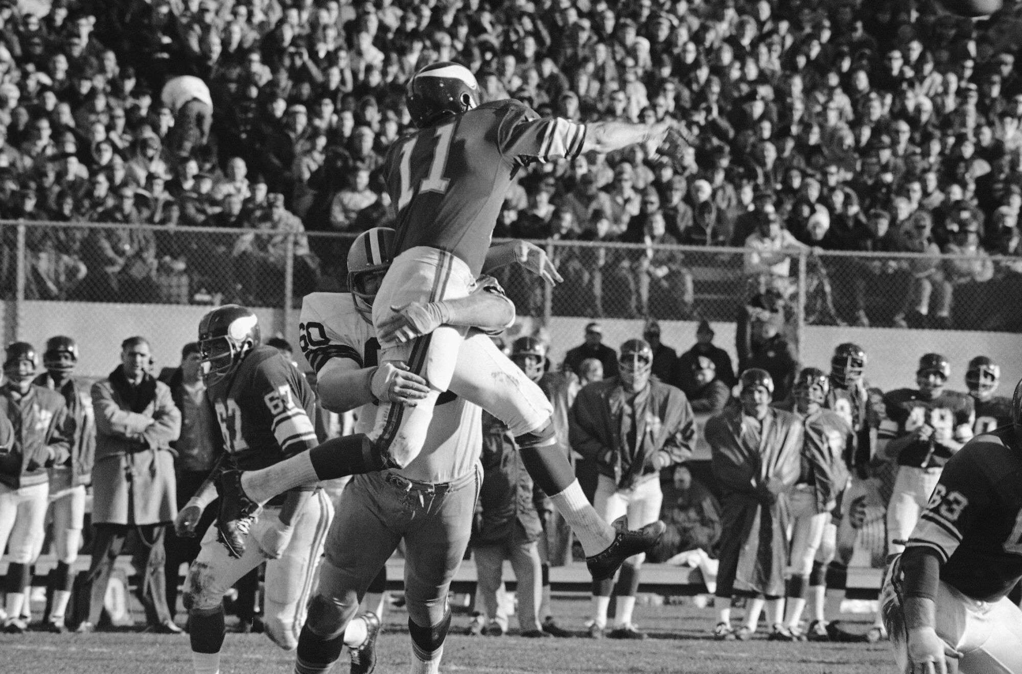 Minnesota Vikings quarterback Joe Kapp is lifted high into the air by the Green Bay Packers' Lee Roy Caffey 