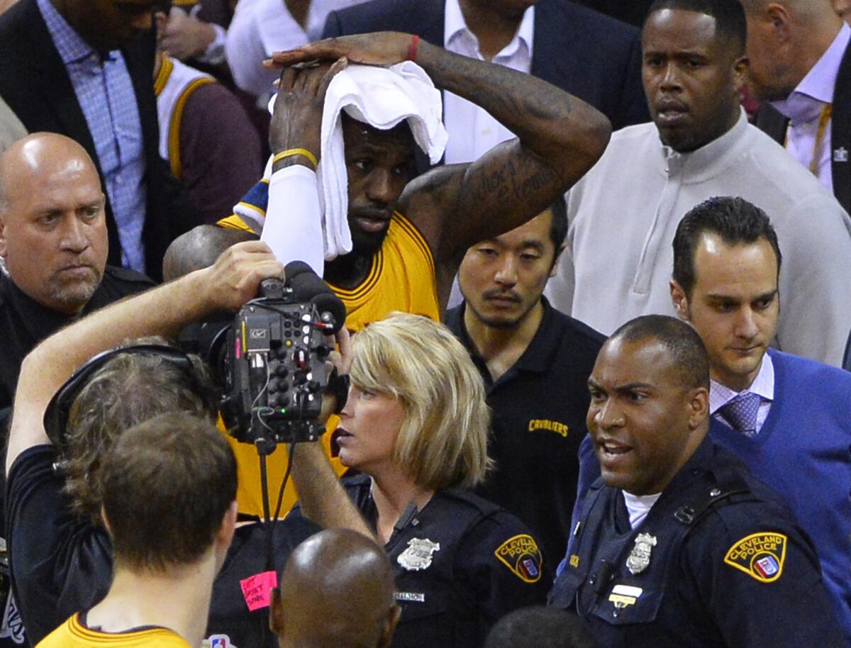 Cavaliers forward LeBron James holds a towel to his head after falling into a cameraman during Game 4 of the NBA Finals on Thursday in Cleveland.