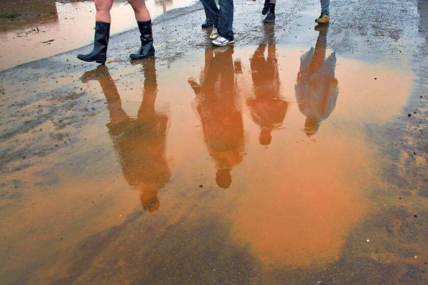 Spectators avoid puddles as they walk through the muddy infield during 2018 Preakness Day at Pimlico Race Course.