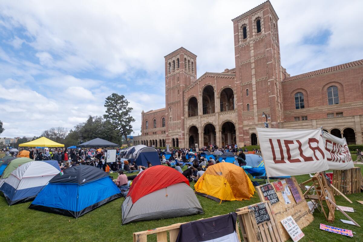 People and tents on a grassy area in front of a building.