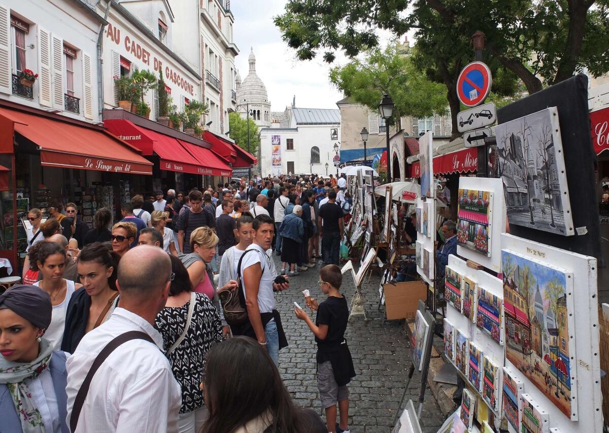 Tourists look at the work of painters in Place du Tertre in the Montmartre district of Paris on August 16, 2015.