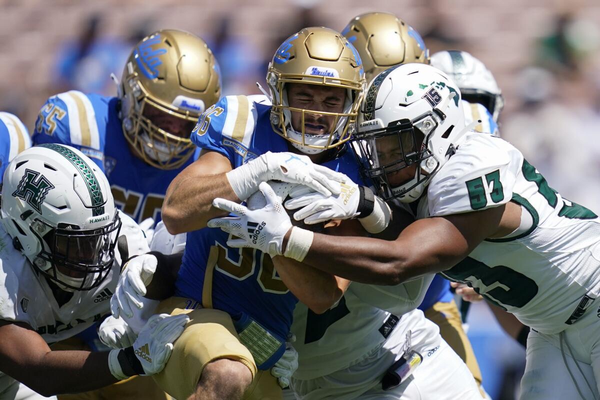 UCLA running back Ethan Fernea is tackled by Hawaii linebacker Darius Muasau.