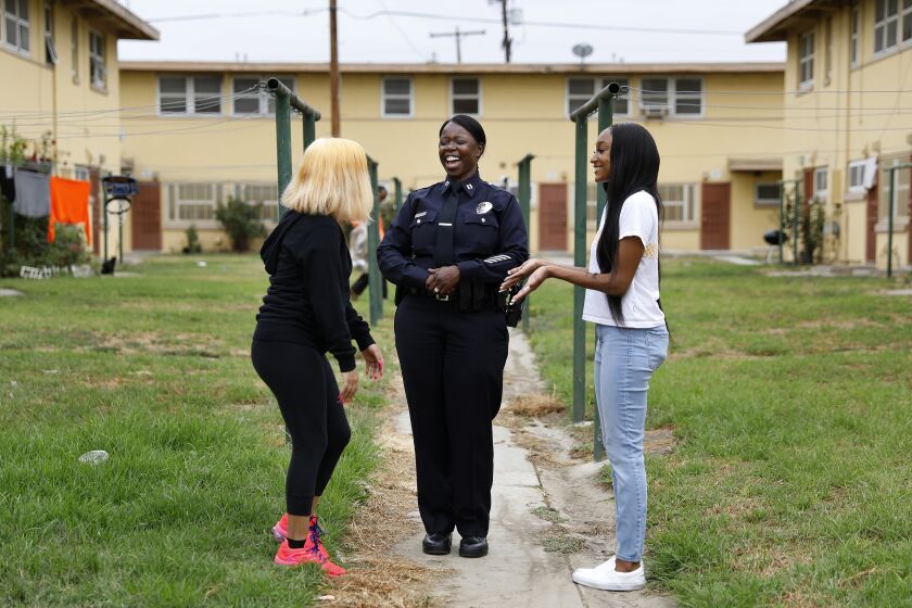 LOS ANGELES-CA-JULY 23, 2020: Emada Tingirides, center, chats with Petra Avelar, 18, left, and Meah Watson, 18, right, at Nickerson Gardens in Watts on Thursday, July 23, 2020. Avelar and Watson are best friends who grew up together in Nickerson Gardens and through Operation Progress will be attending college on the east coast this Fall. A community policing program known as Community Safety Partnership will now have its own bureau within the LAPD, headed by Emada Tingirides, whom will become the LAPD's second Black female deputy chief.(Christina House / Los Angeles Times)
