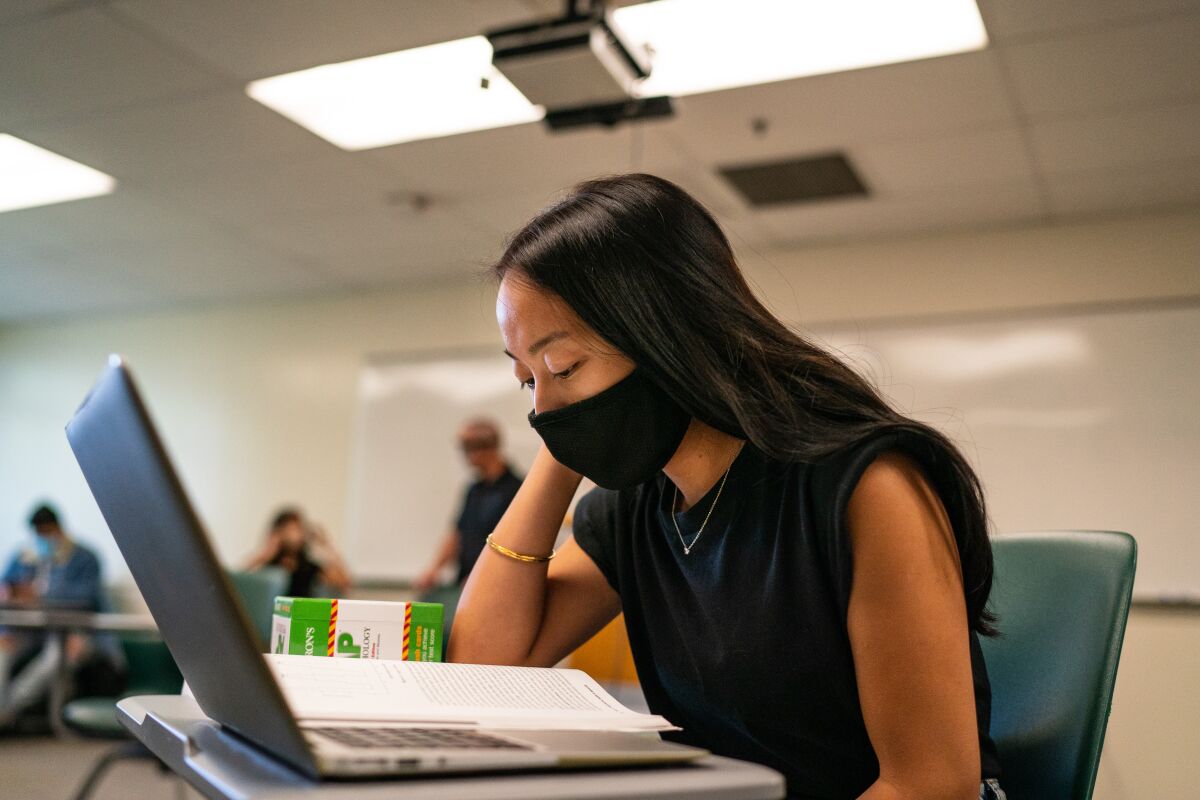 Nichola Soleta looks over a computer and textbook in a classroom
