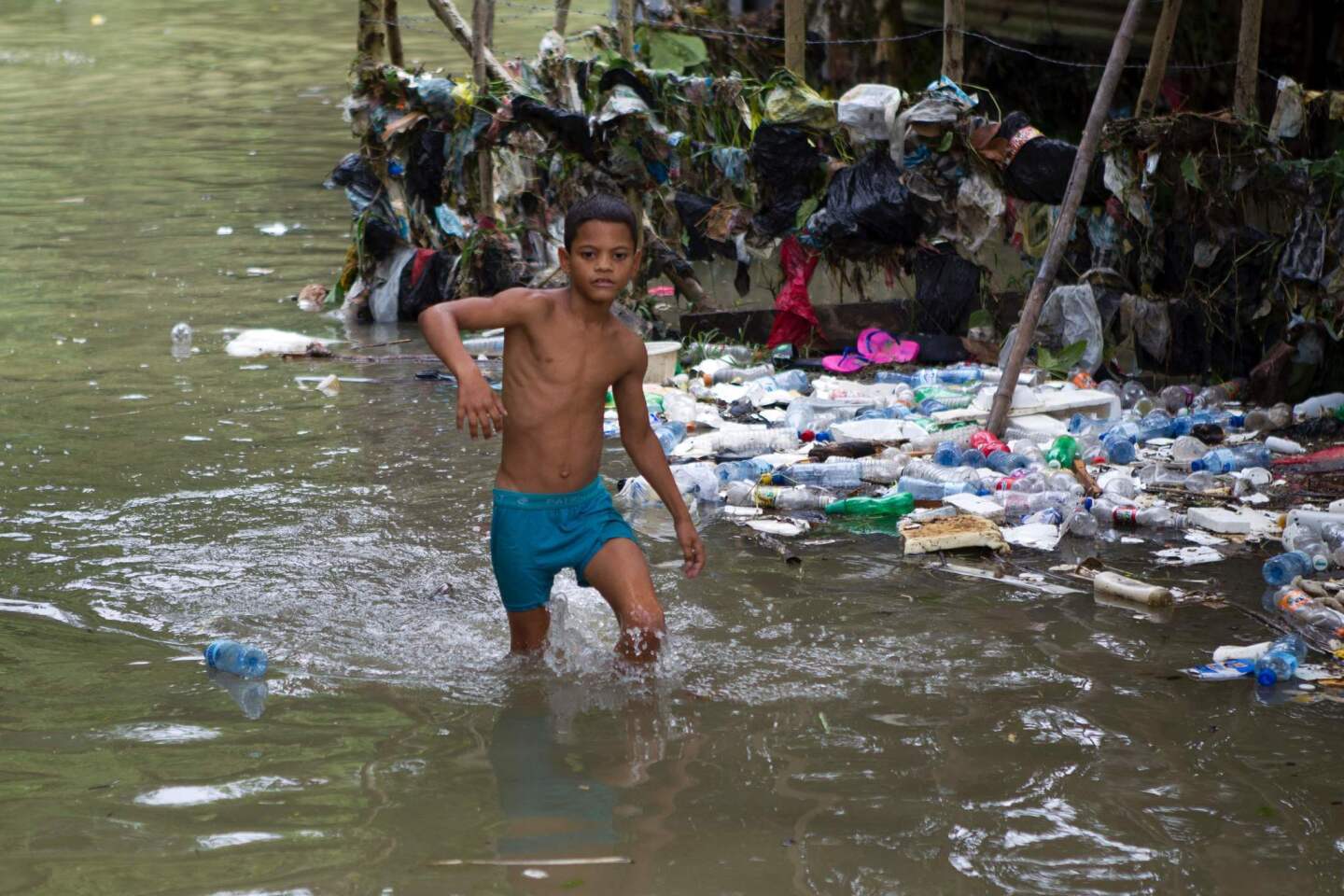 A boy wades through the water the flooded neighbourhood of La Puya, Santo Domingo, on Oct. 4, 2016 after the passage of Hurricane Matthew through Hispaniola -- the island that the Dominican Republic shares with Haiti.