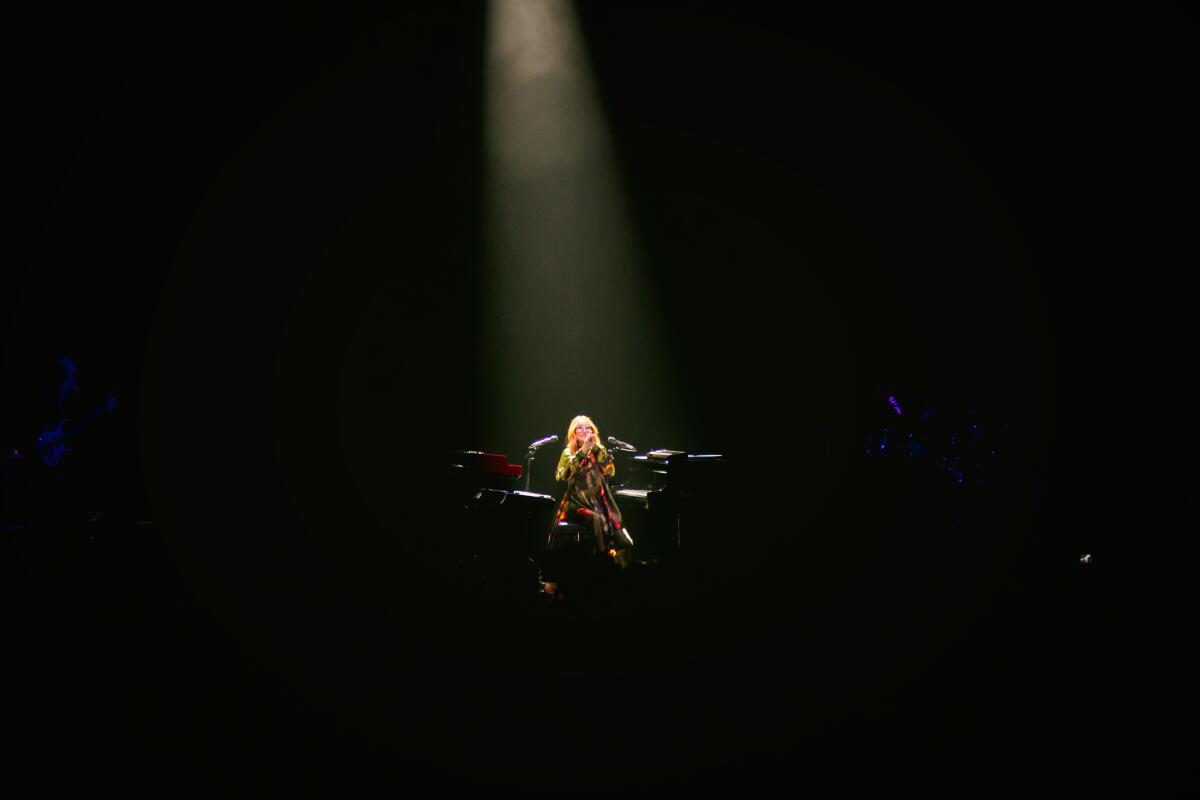 A woman in the spotlight on a dark stage.