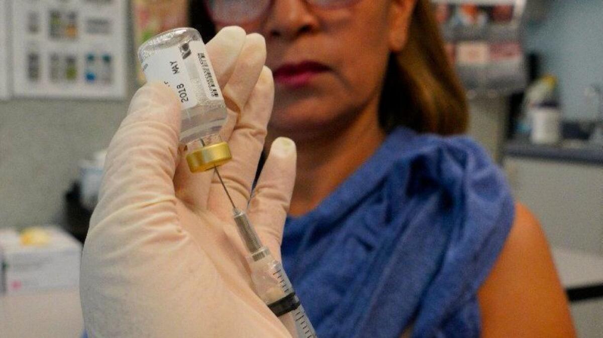 Registered nurse Maria Baeza prepares a syringe with the flu vaccine at the South Region Public Health and Human Services Agency in Chula Vista.