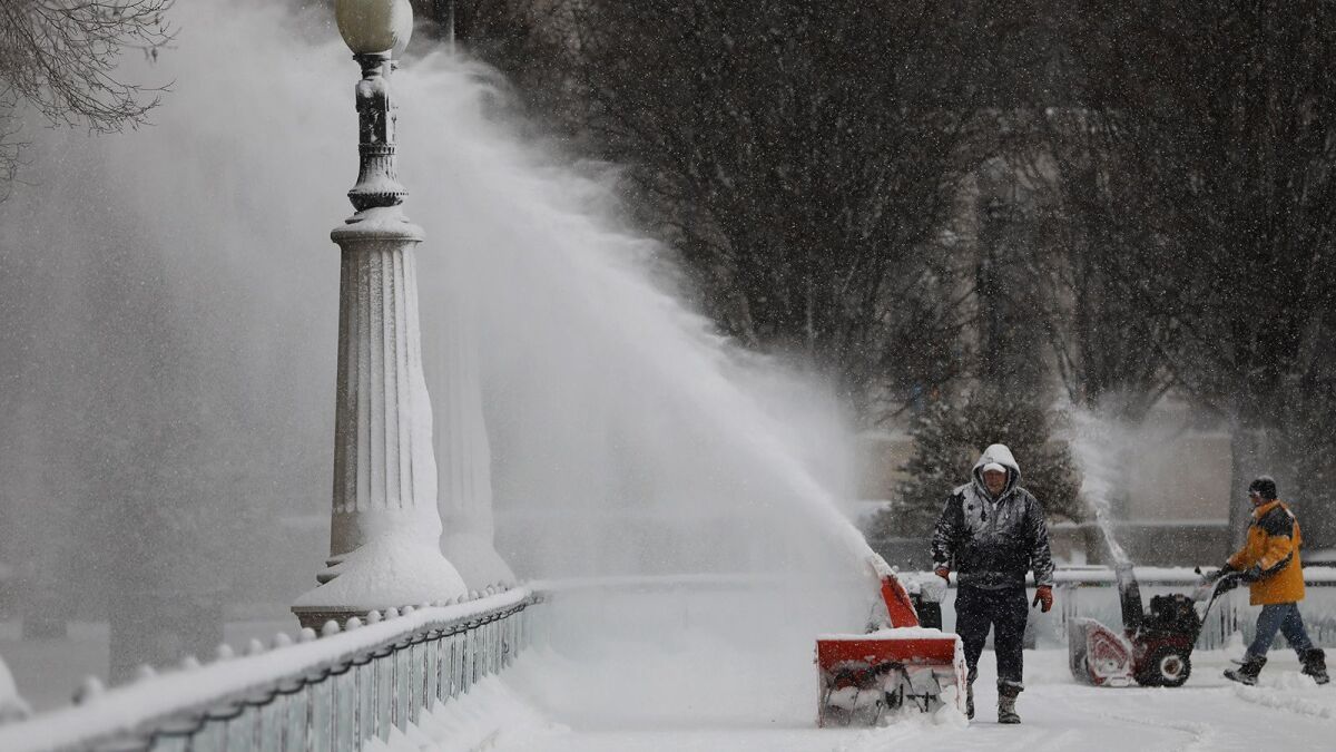 Men use blowers to clear the snow from the skating rink in Millennium Park in Chicago.