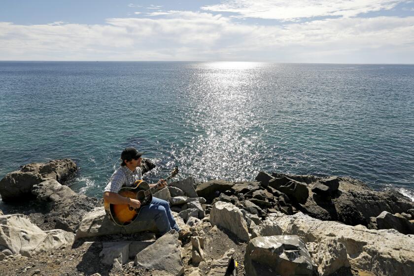 Oxnard, California-Nov. 17, 2021-Jeffrey Meyer, of Salinas, CA, take a break from work to play music on Pacific Coast Highway at Point Mugu, just south of Oxnard on Nov. 22, 2021. He comes to the point wherever he's in town on business. Santa Ana winds are bringing warm weather to Southern California, (Carolyn Cole / Los Angeles Times)