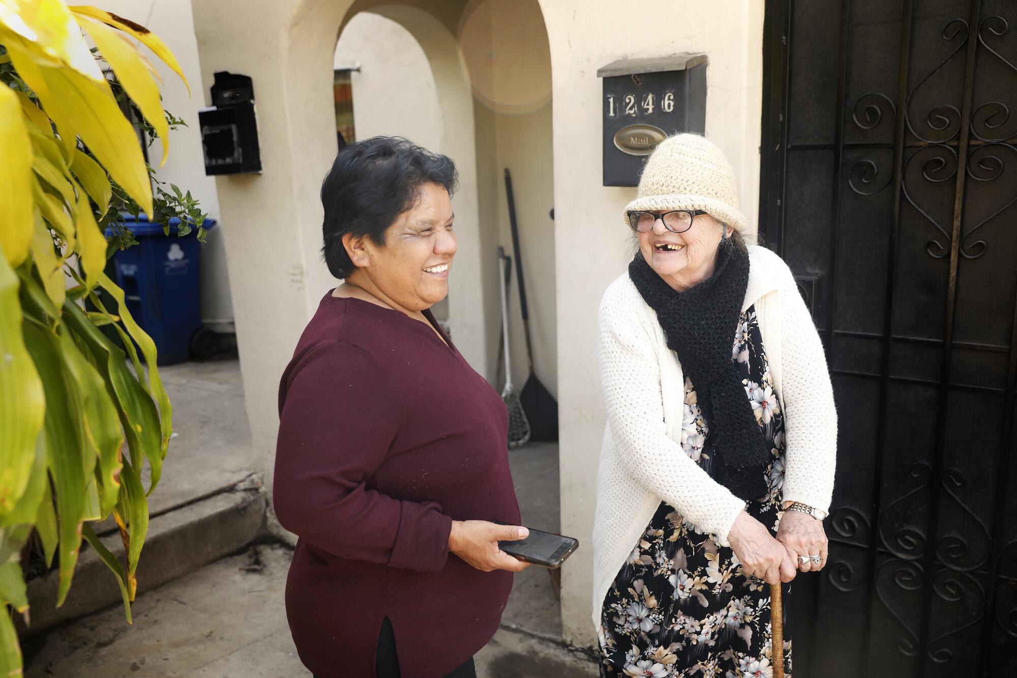 Neighbors Elvira Rincon, left, and Virginia Watson, right, share a laugh outside of Watson's apartment.