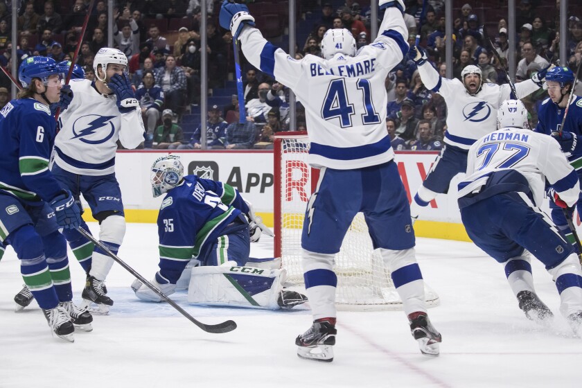 Tampa Bay Lightning's Taylor Raddysh, back left, Pierre-Edouard Bellemare (41), of France, Victor Hedman (77), of Sweden, and Pat Maroon, back right, celebrate Hedman's goal against Vancouver Canucks goalie Thatcher Demko (35) as Canucks' Brock Boeser (6) and Quinn Hughes (43) watch during the first period of an NHL hockey game in Vancouver, British Columbia, Sunday, March 13, 2022. (Darryl Dyck/The Canadian Press via AP)