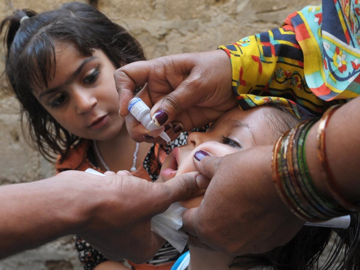 A Pakistani health worker administers polio vaccine drops to a child in Karachi. Pakistan is one of three countries where the disease is prevalent.