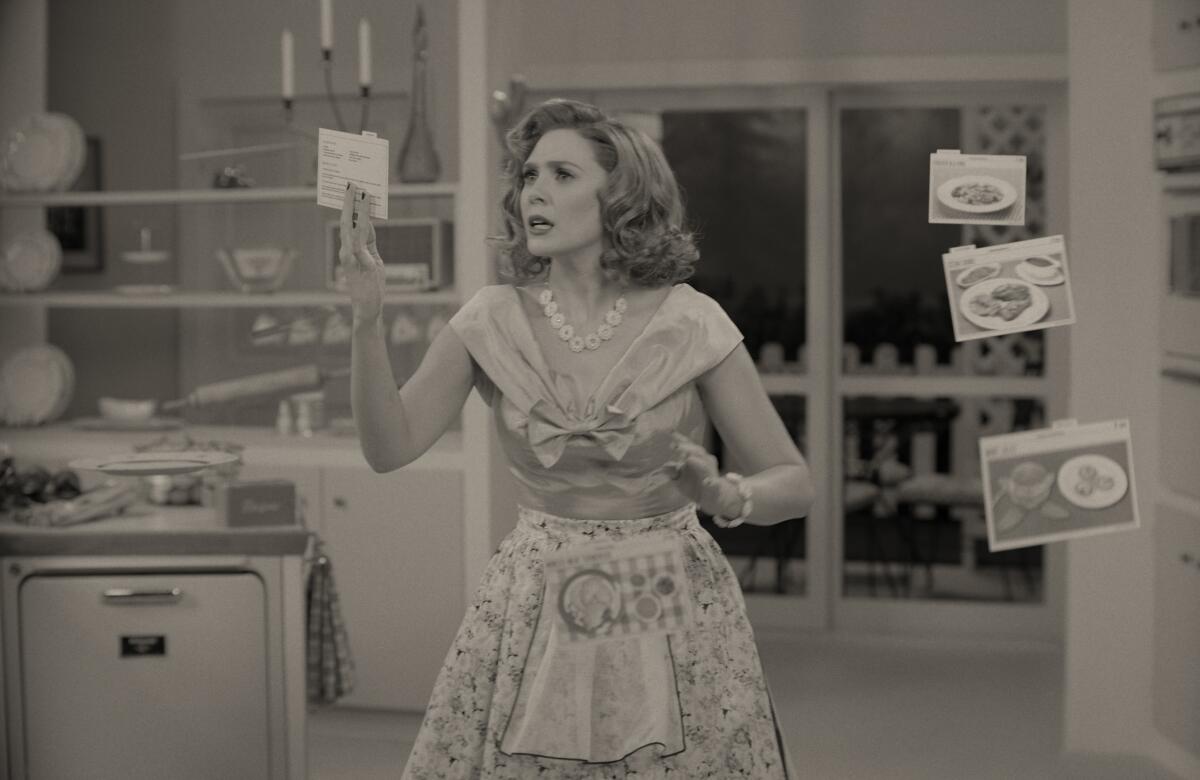 A black-and-white photo of a woman who looks like a 1950s housewife in her kitchen, with recipe cards whirling around her.