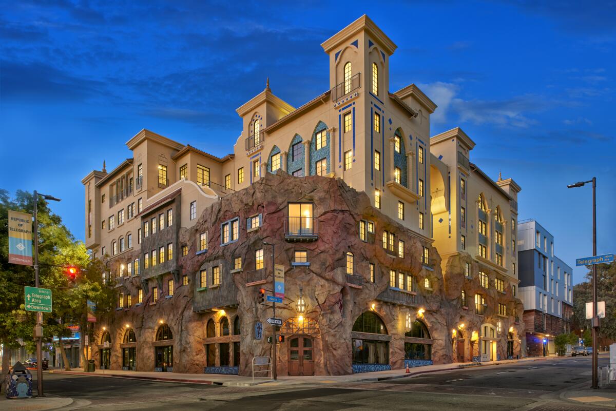 A street view of a castle-like apartment complex with a facade resembling a craggy cliffside