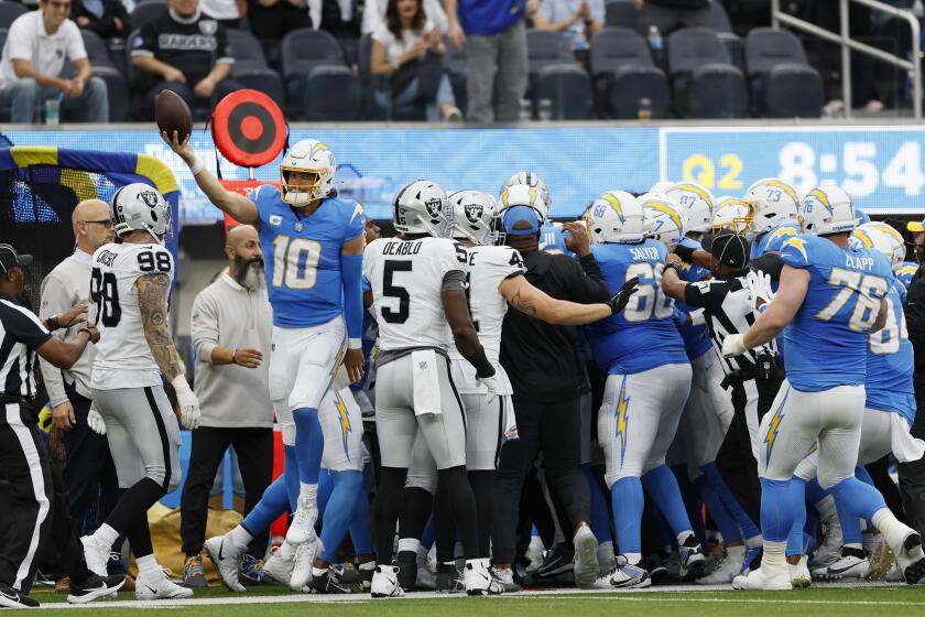 The Chargers' Justin Herbert (10) emerges after he was hit out of bounds by the Raiders' Jerry Tillery (90), who was ejected.