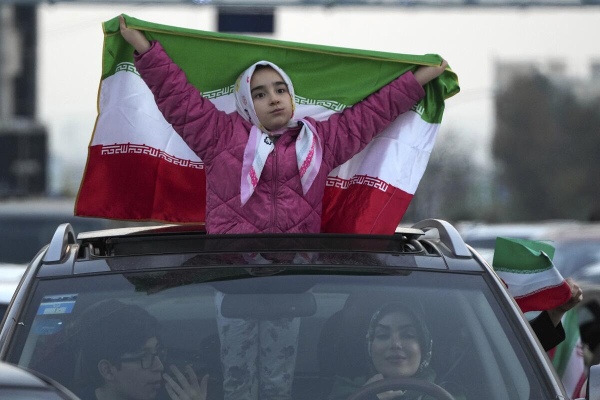 A girl holds up her country's flag during a street celebration in Tehran after Iran's victory over Wales.