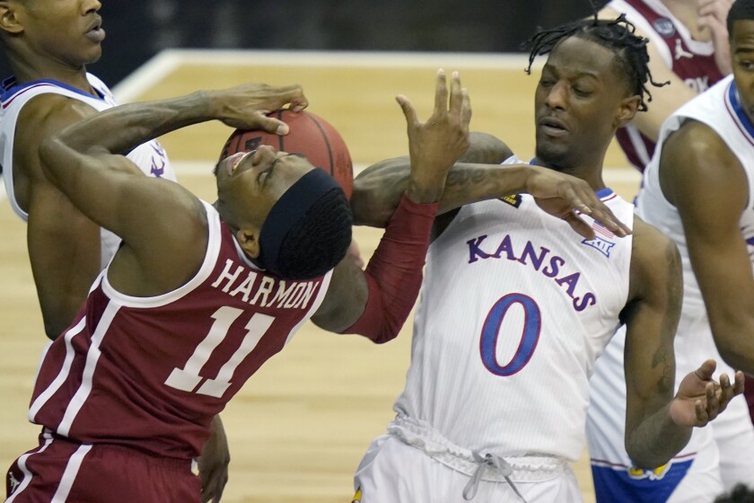 Oklahoma guard De'Vion Harmon (11) is called for traveling while covered by Kansas guard Marcus Garrett (0) during the first half of an NCAA college basketball game in the quarterfinal round of the Big 12 men's tournament in Kansas City, Mo., Thursday, March 11, 2021. (AP Photo/Orlin Wagner)