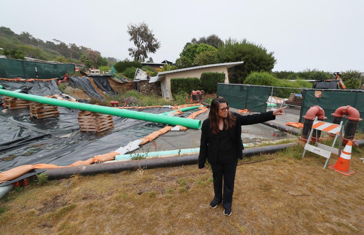 A woman stands amid tarps and construction equipment and gestures with her hand.