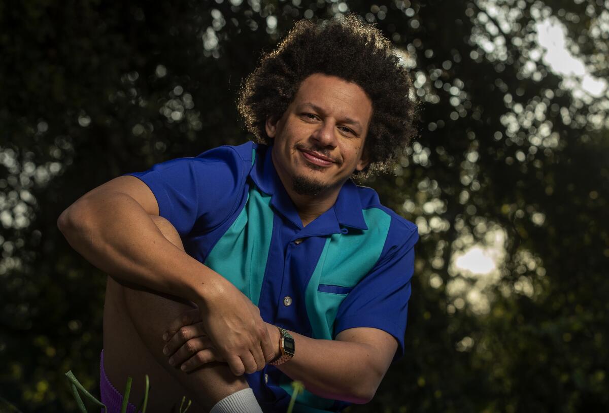 Eric Andre in a collared shirt posing in front of trees