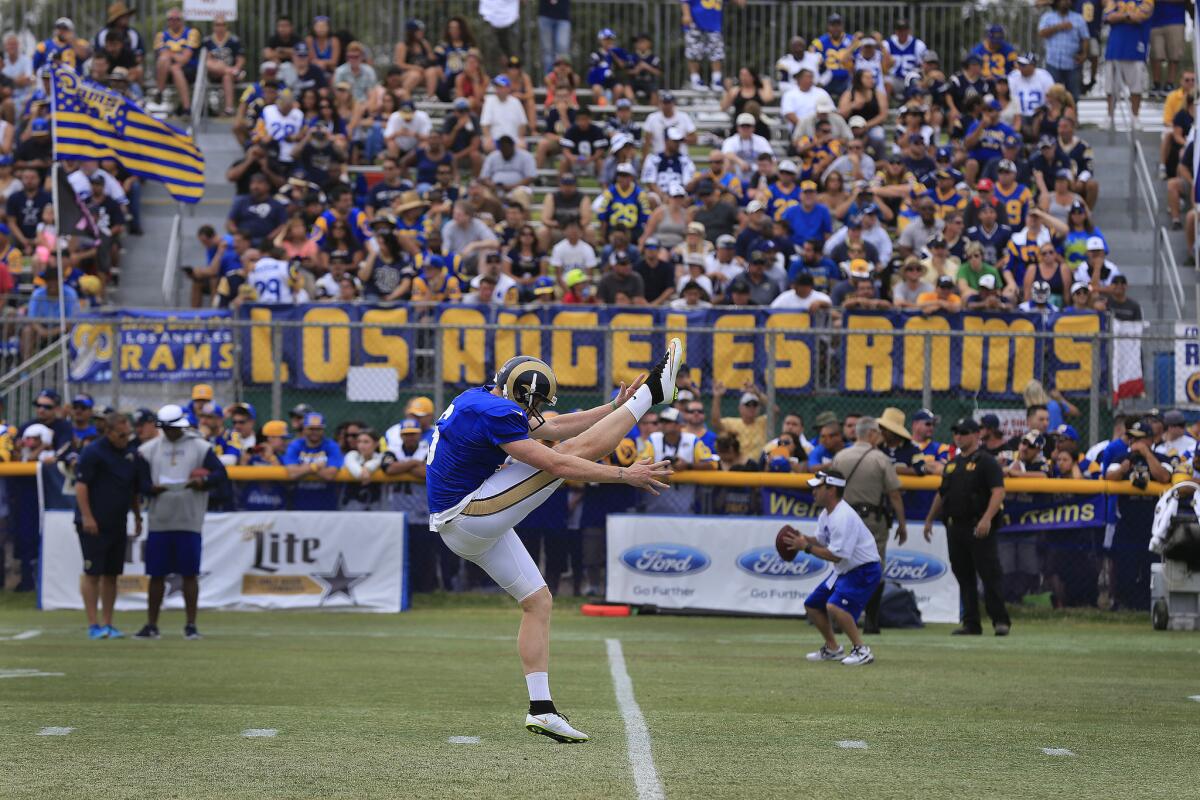 St. Louis punter Johnny Hekker gets off a kick with a Los Angeles Rams banner in the background during a combined practice session with the Dallas Cowboys.