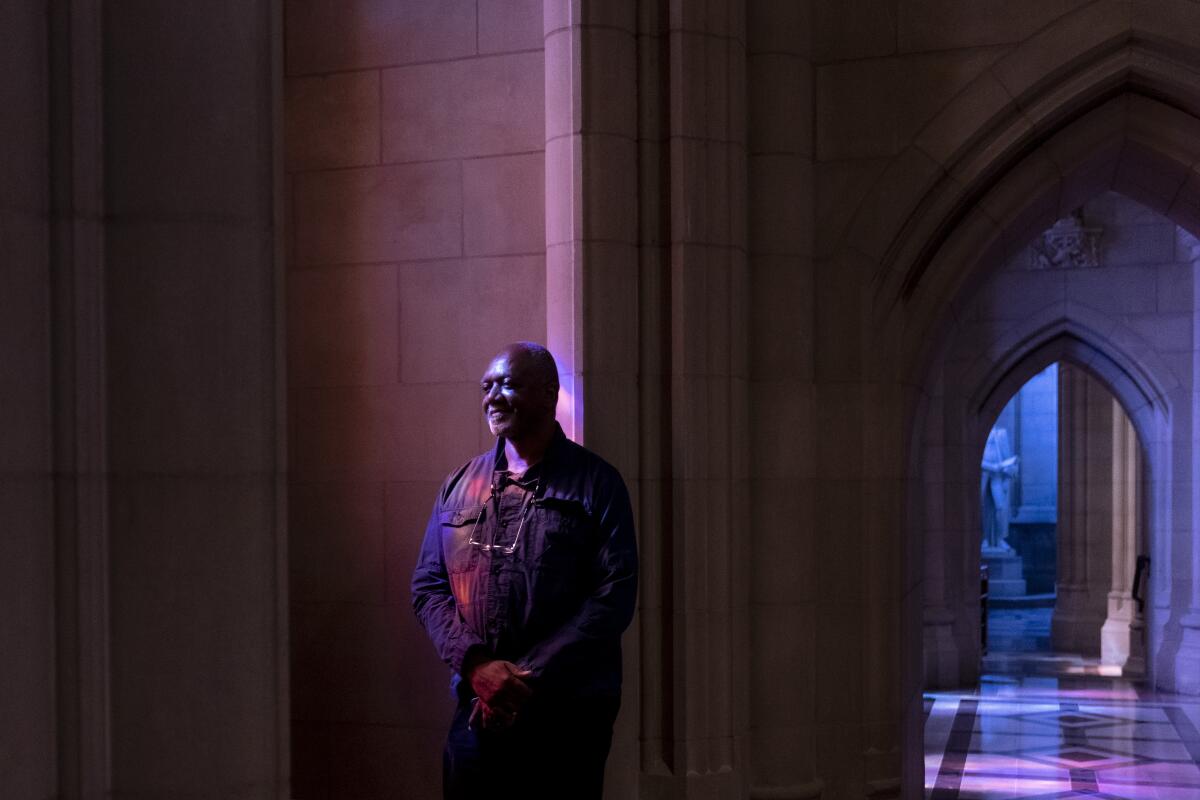 Artist Kerry James Marshall stands before a gently illuminated Gothic arch inside Washington National Cathedral