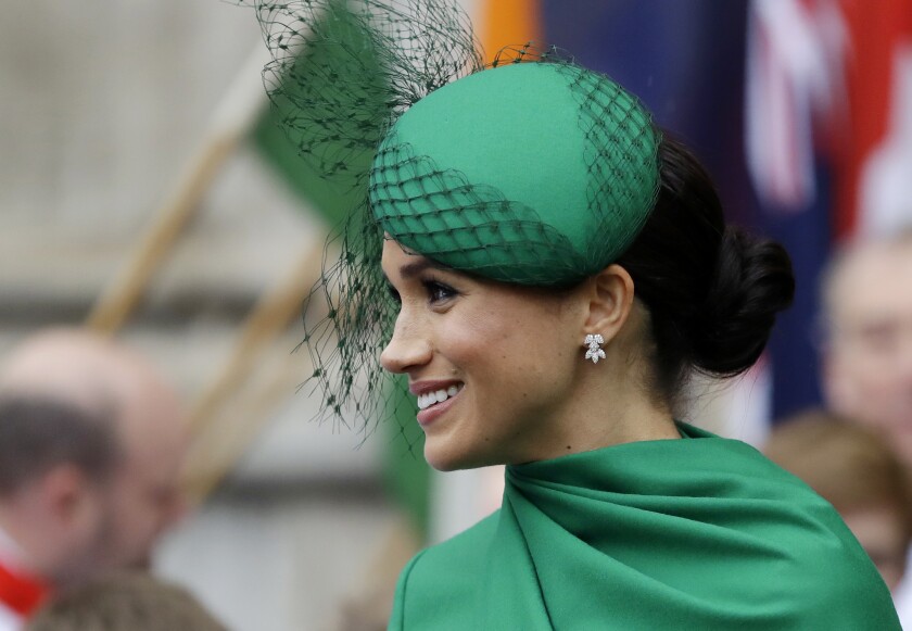 Meghan wears a green dress and green hat with black netting at a function at Westminster Abbey in London.