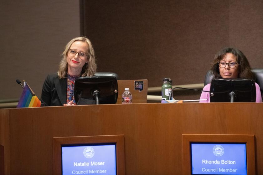 Council members Natalie Moser, left, and Rhonda Bolton sit at the dais with LGBTQ Pride flags on their desks during Tuesday night's Huntington Beach City Council meeting.
