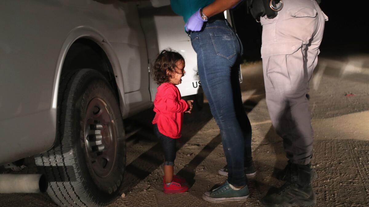 A 2-year-old Honduran asylum seeker cries as her mother is searched and detained near the U.S.-Mexico border on June 12 in McAllen, Texas.