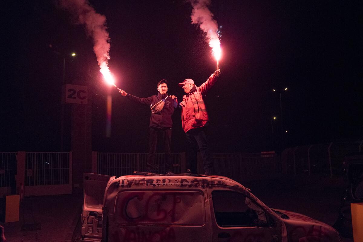 Protesters with flares stand on a vandalized car during a blockade of the port of Marseille in southern France on Thursday.