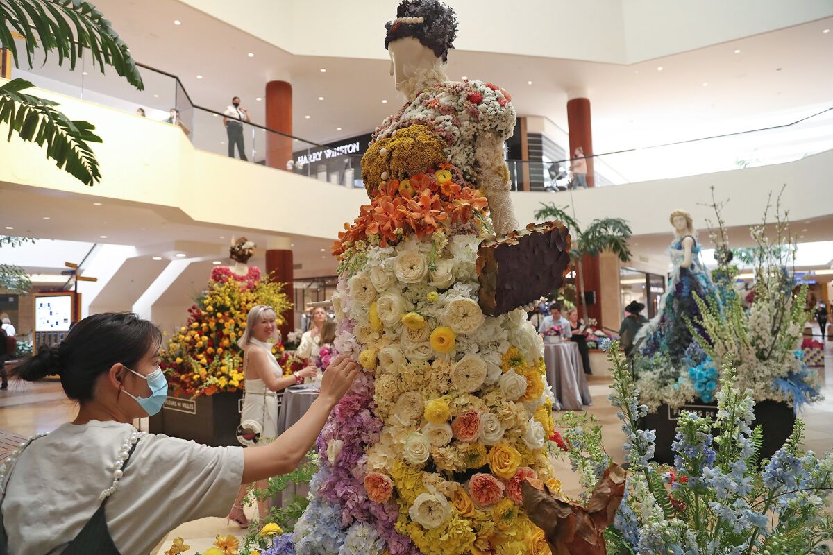 A designer touches up a Helena Modjeska figure at the "Fleurs de Villes FEMMES" floral exhibit. 