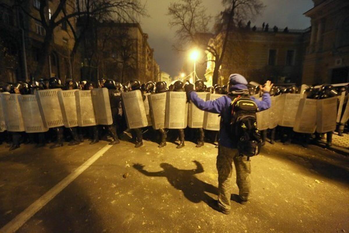 A protester faces riot troops protecting Ukraine's presidential administration building in Kiev.