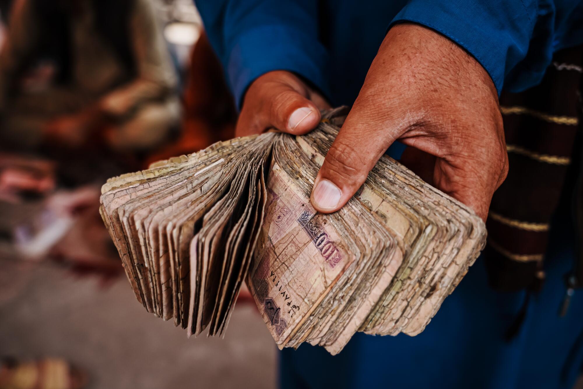 Hands hold a wad of Afghan cash 