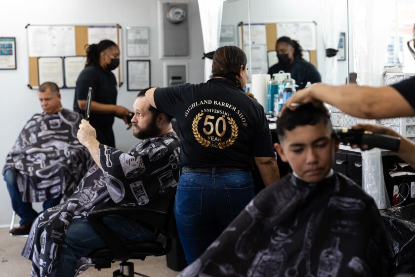 Ryan Marsh holds up a mirror to check out his new haircut during the 50th anniversary of Highland Barber Shop at National City on Saturday, July 16, 2022.