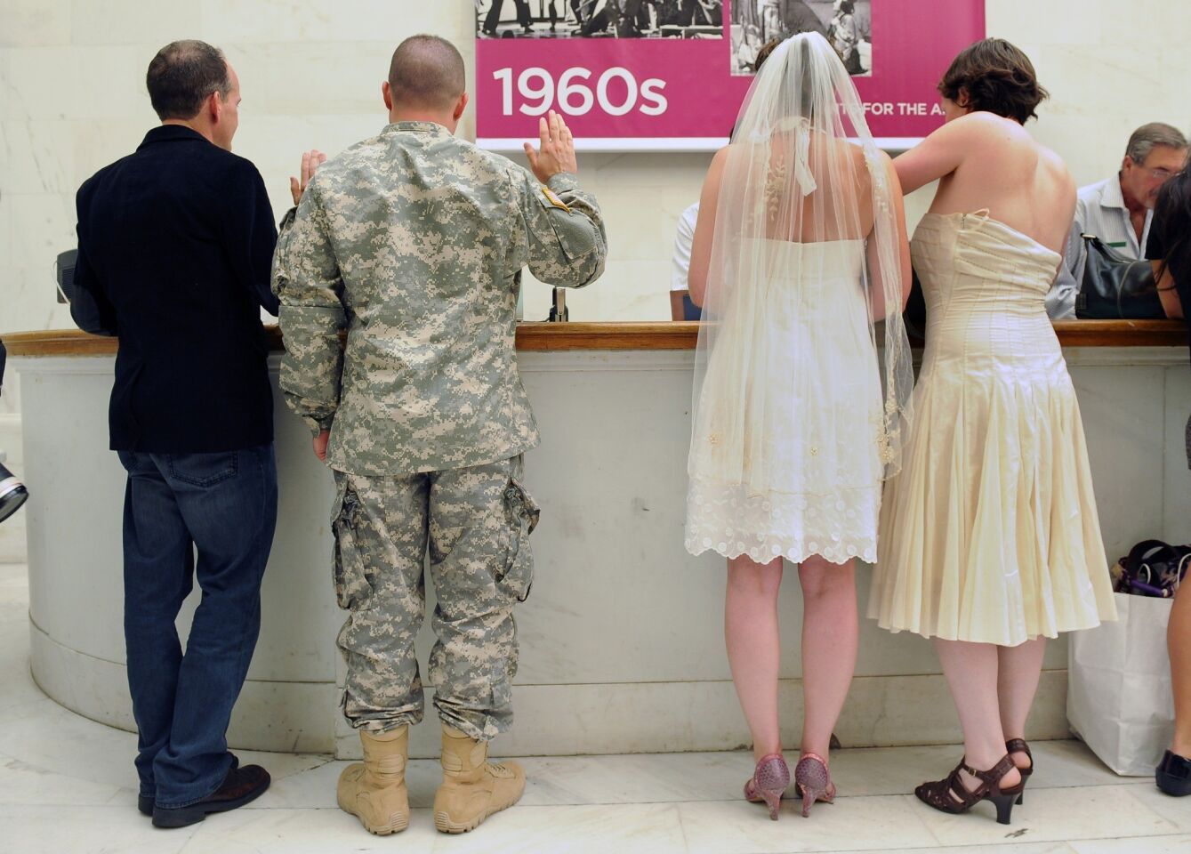 Army Sgt. Michael Potoczniak and Todd Saunders, left; and Cynthia Wides, in the veil, and Elizabeth Carey wait to get married at City Hall in San Francisco on Saturday
