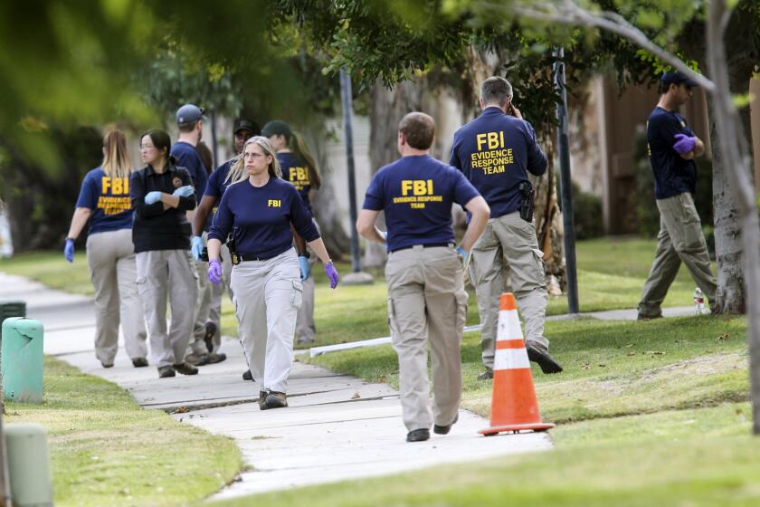 FBI agents search outside a home in connection to the shootings in San Bernardino on Dec. 3 in Redlands.