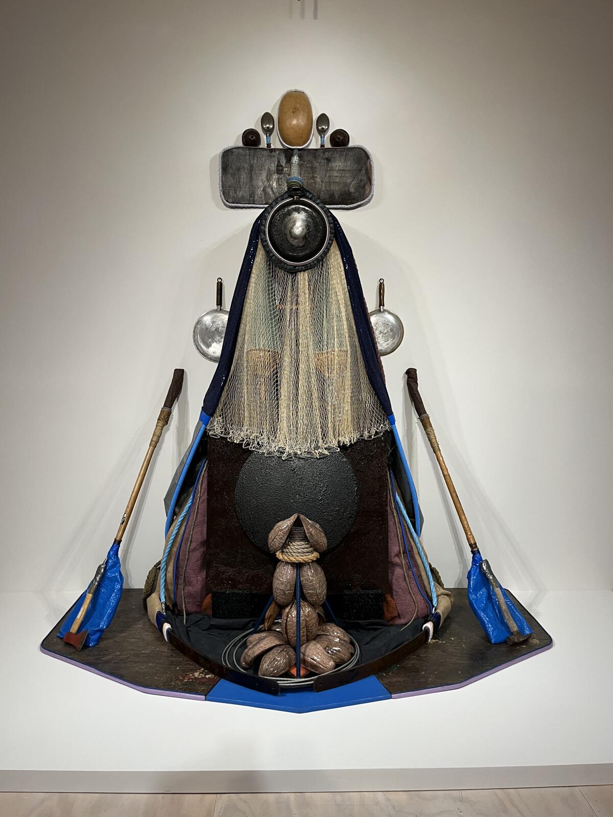 An assemblage made from tarps and old cookware evokes the figure of the Virgin Mary