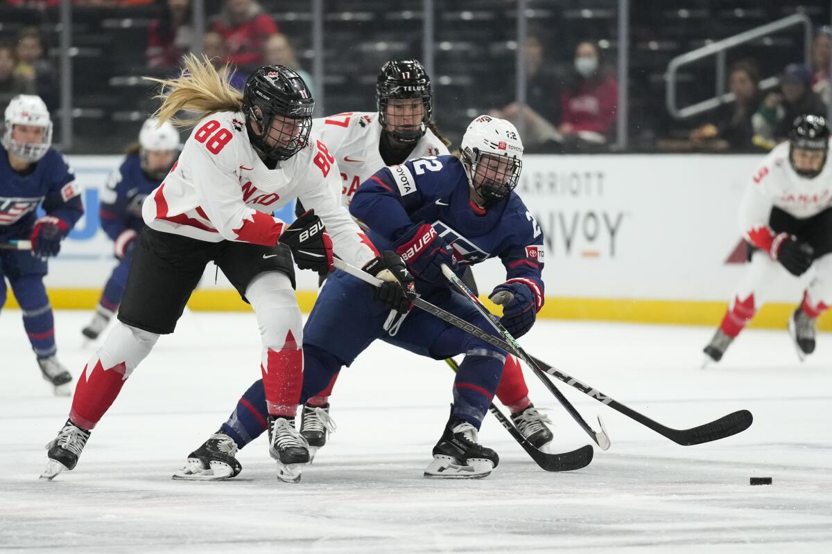 U.S. forward Tessa Janecke tries to control the puck in front of Canada's Julia Gosling (88) and Ella Shelton.